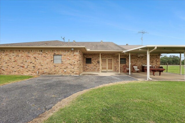 7385 Fannett Rd, Beaumont, TX 77705 - back of property featuring a yard, a patio area, brick siding, and roof with shingles