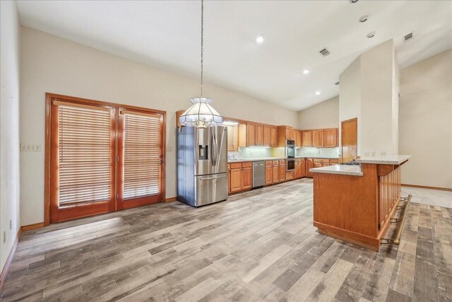 7385 Fannett Rd, Beaumont, TX 77705 - kitchen featuring appliances with stainless steel finishes, brown cabinetry, light countertops, a peninsula, and a chandelier
