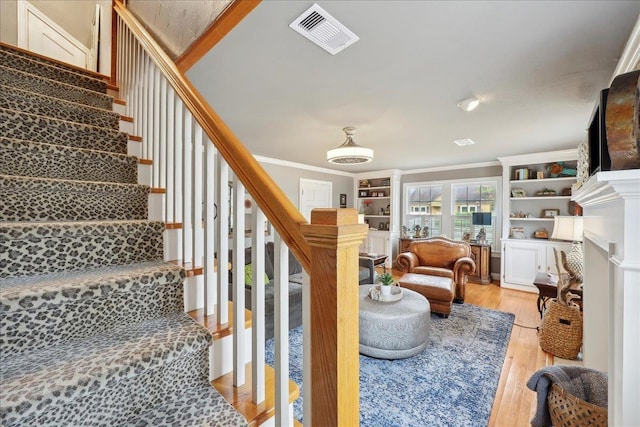 stairs featuring visible vents, wood finished floors, and crown molding