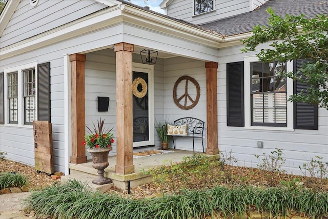 entrance to property featuring covered porch and a shingled roof