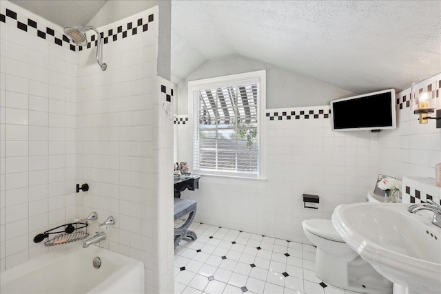 bathroom featuring a textured ceiling, tile walls, lofted ceiling, and a sink