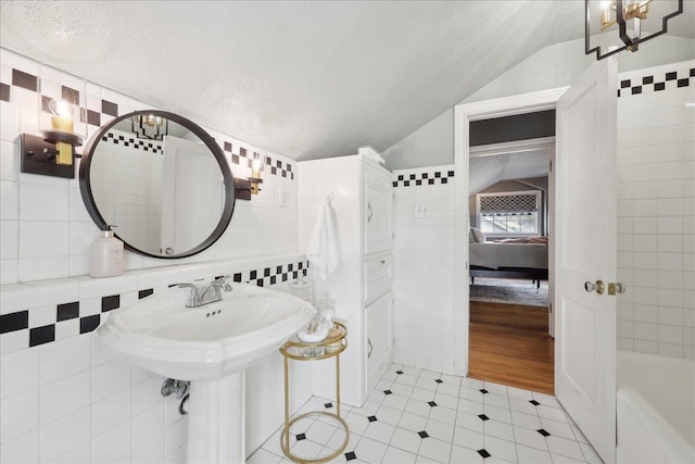 full bath featuring tile walls, a bath, vaulted ceiling, and a textured ceiling