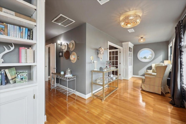 sitting room featuring wood finished floors, visible vents, and baseboards