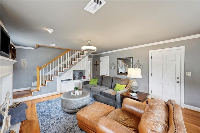 living area with visible vents, crown molding, baseboards, stairs, and wood finished floors