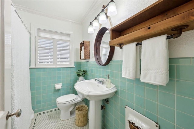 bathroom with tile patterned floors, toilet, tile walls, wainscoting, and crown molding