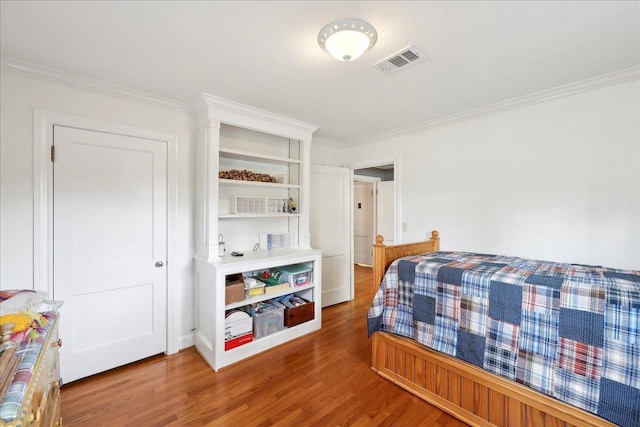 bedroom with visible vents, crown molding, and wood finished floors