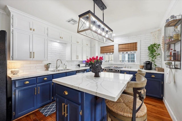 kitchen with blue cabinets, a sink, tasteful backsplash, a center island, and gas stove