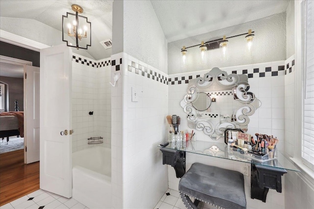 ensuite bathroom with tile patterned flooring, tile walls, visible vents, and connected bathroom