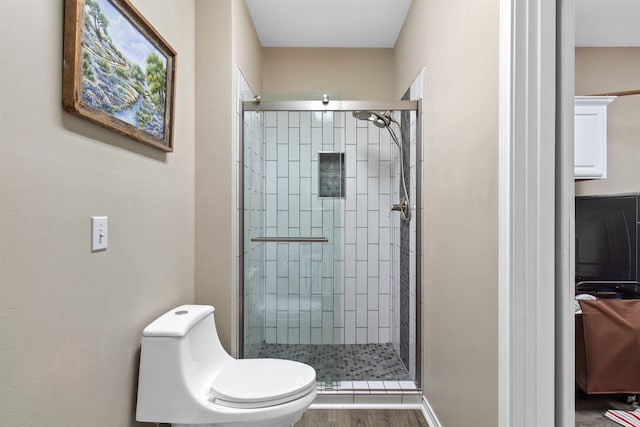 bathroom featuring walk in shower, wood-type flooring, and toilet