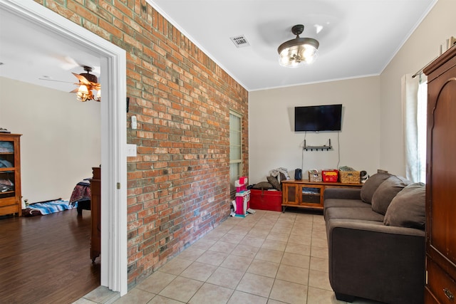 living room featuring light hardwood / wood-style flooring, crown molding, and brick wall