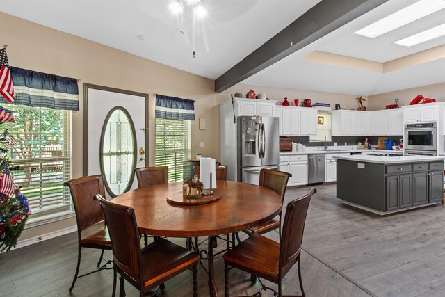 dining room with dark hardwood / wood-style floors, ceiling fan, sink, and a skylight