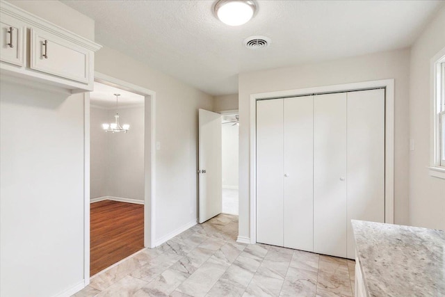 unfurnished bedroom featuring an inviting chandelier, a textured ceiling, and a closet