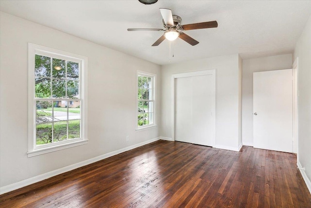 unfurnished bedroom featuring multiple windows, ceiling fan, a closet, and dark hardwood / wood-style floors