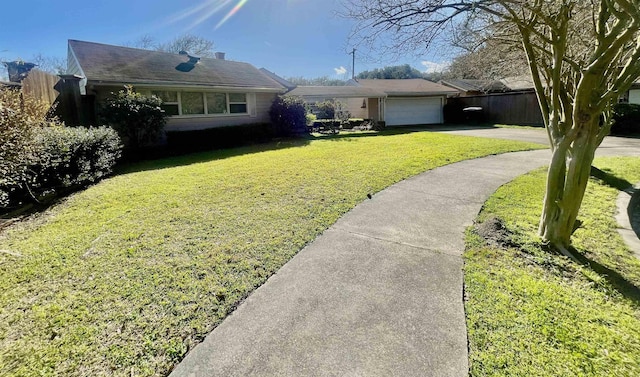 ranch-style house featuring a front yard, fence, driveway, and an attached garage