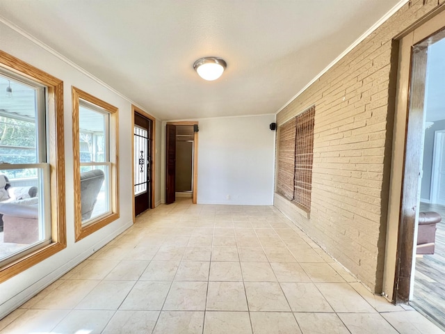 spare room featuring light tile patterned floors, brick wall, and crown molding