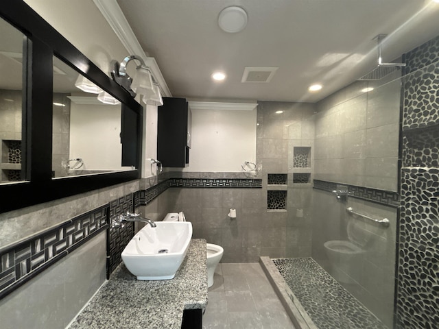 bathroom with sink, tile walls, toilet, ornamental molding, and tiled shower