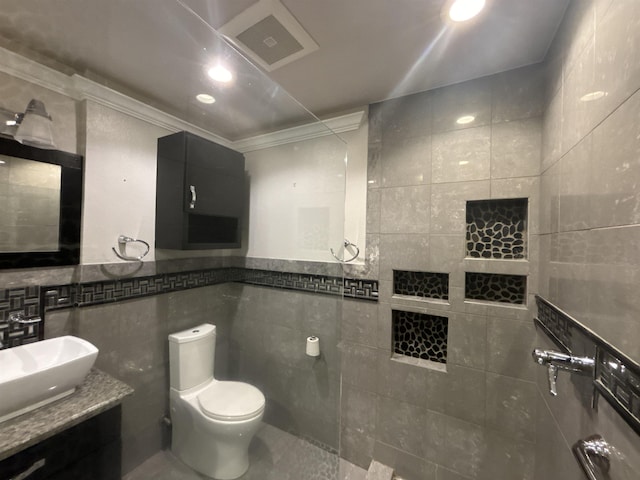 bathroom featuring toilet, tile patterned flooring, tile walls, crown molding, and vanity