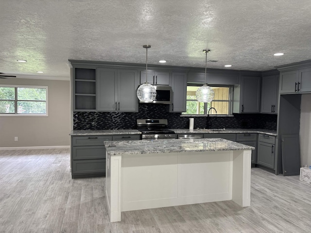 kitchen with light stone counters, appliances with stainless steel finishes, a center island, and gray cabinetry