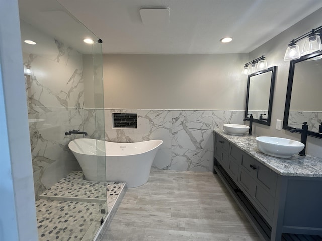 bathroom featuring tile walls, a washtub, and vanity