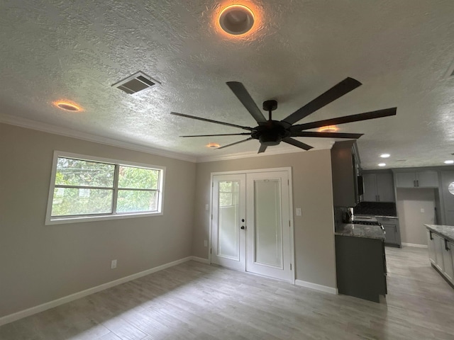 interior space with a textured ceiling, crown molding, and light hardwood / wood-style floors