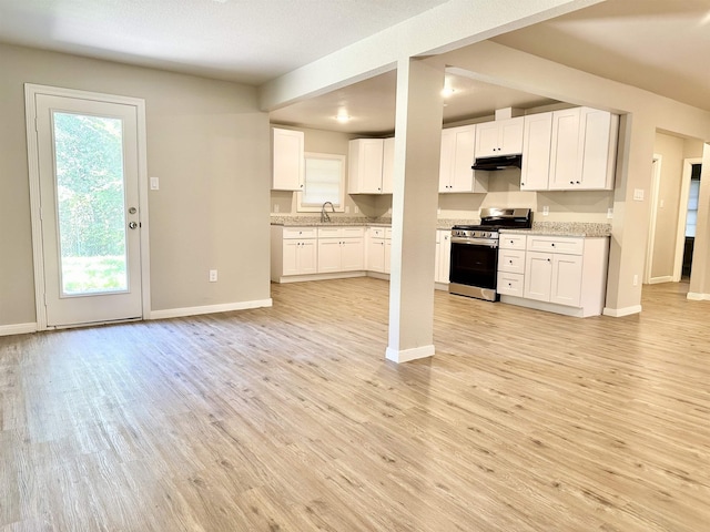 kitchen featuring a wealth of natural light, white cabinets, and stainless steel range with gas stovetop