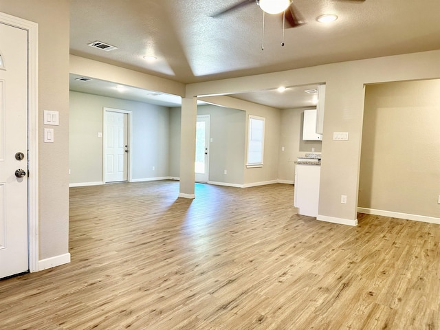 unfurnished living room with a textured ceiling, light hardwood / wood-style floors, and ceiling fan