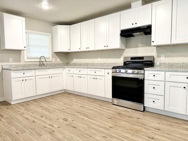 kitchen with light stone counters, sink, light hardwood / wood-style flooring, white cabinets, and stainless steel stove