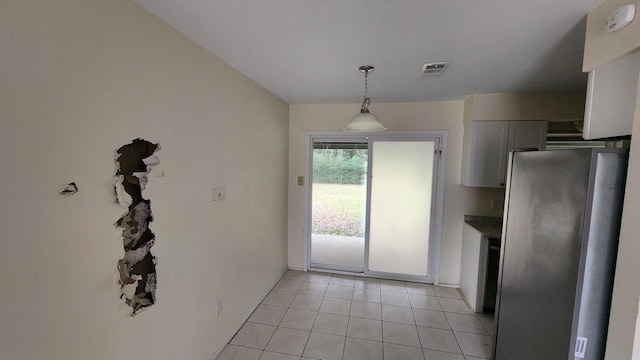 kitchen with white cabinetry, stainless steel fridge, decorative light fixtures, and light tile patterned floors