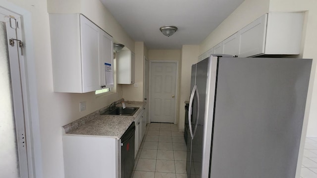 kitchen featuring sink, light tile patterned floors, stainless steel refrigerator, and white cabinets