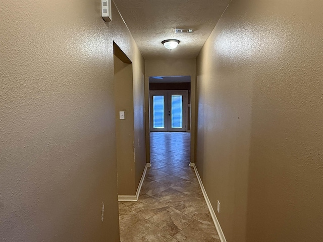 hall featuring a textured ceiling and french doors