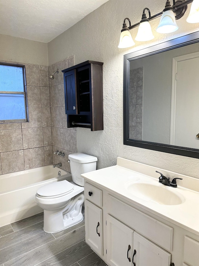 full bathroom featuring vanity, tiled shower / bath combo, a textured ceiling, and toilet