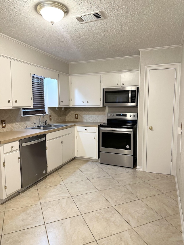 kitchen featuring sink, ornamental molding, a textured ceiling, appliances with stainless steel finishes, and white cabinetry