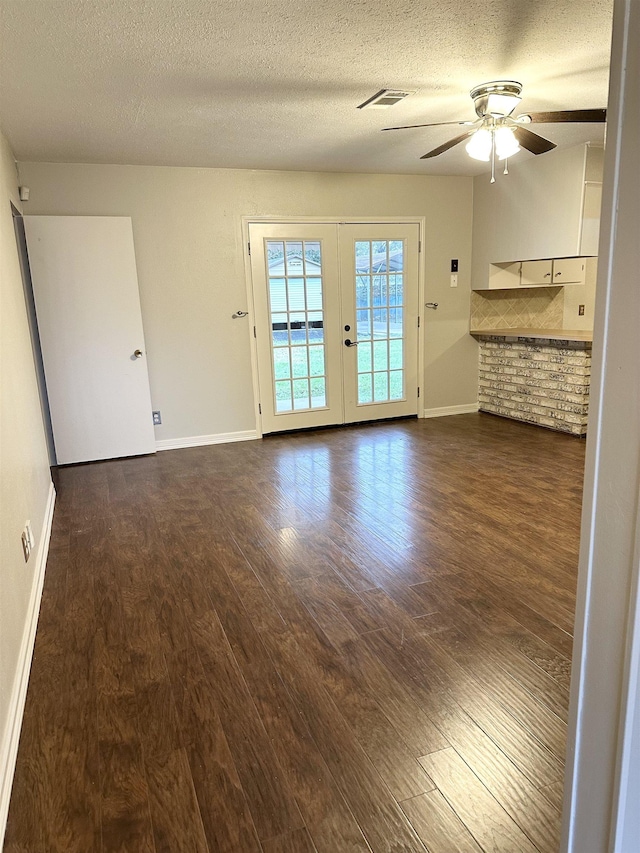 spare room featuring french doors, dark hardwood / wood-style flooring, a textured ceiling, and ceiling fan