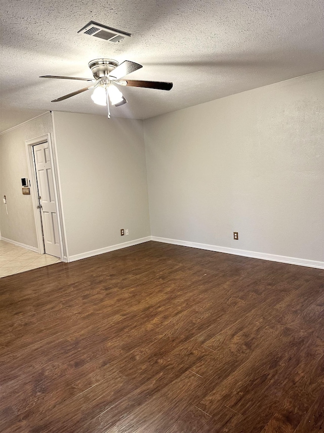 empty room featuring a textured ceiling, ceiling fan, and dark wood-type flooring