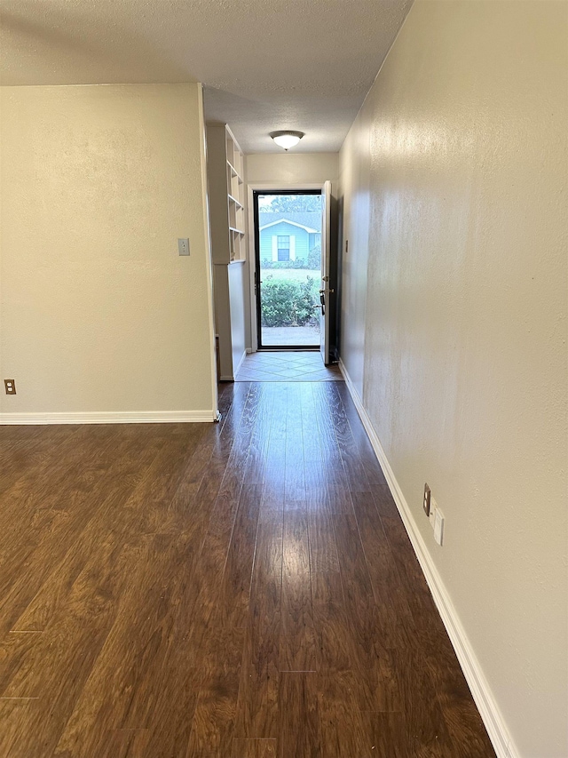 hall with built in features, dark hardwood / wood-style flooring, and a textured ceiling