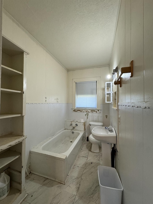 bathroom featuring a textured ceiling, toilet, a bathtub, and a bidet