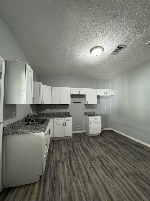 kitchen featuring dark hardwood / wood-style flooring, sink, white cabinets, and dark stone countertops