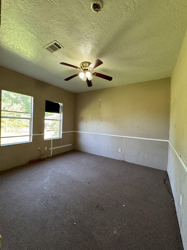 carpeted spare room with a textured ceiling and ceiling fan