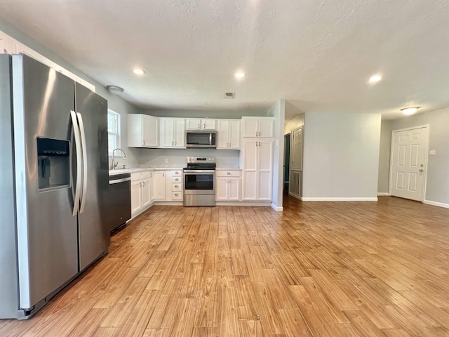 kitchen featuring light hardwood / wood-style flooring, stainless steel appliances, white cabinetry, and sink