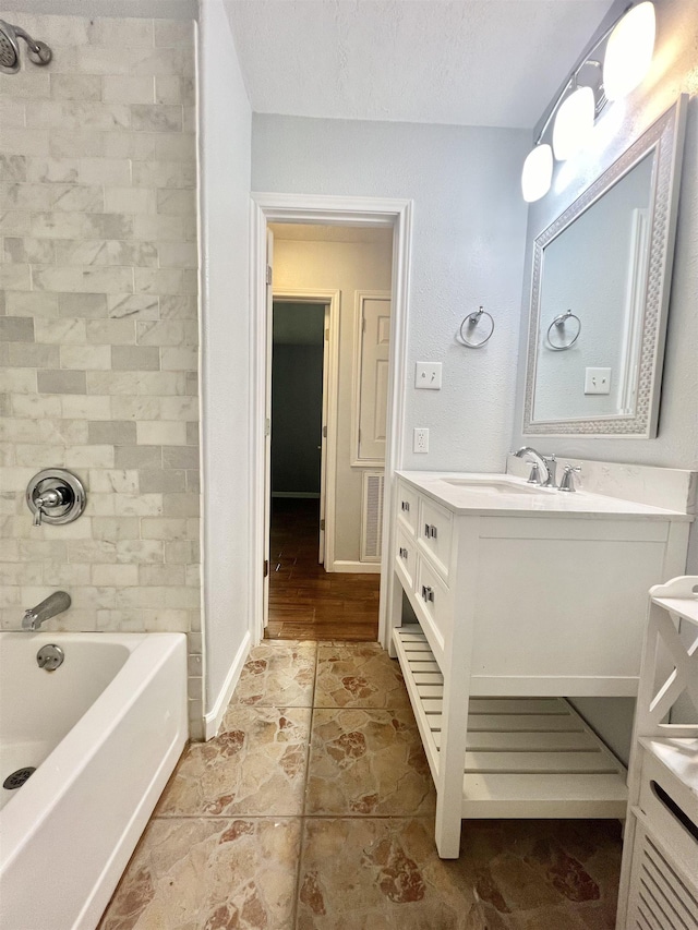 bathroom featuring a textured ceiling, vanity, and tiled shower / bath