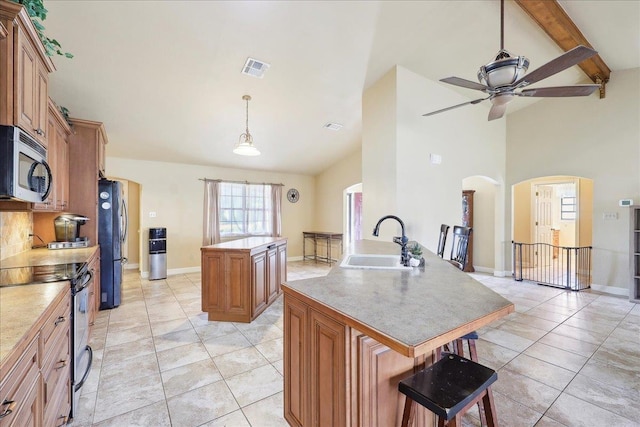 kitchen featuring light tile patterned flooring, appliances with stainless steel finishes, pendant lighting, an island with sink, and sink