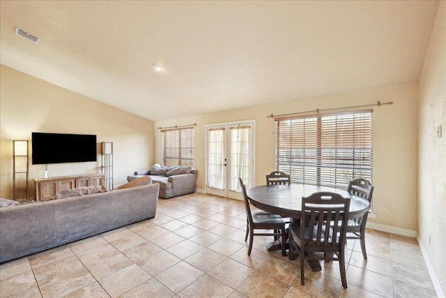 tiled dining space featuring vaulted ceiling and french doors