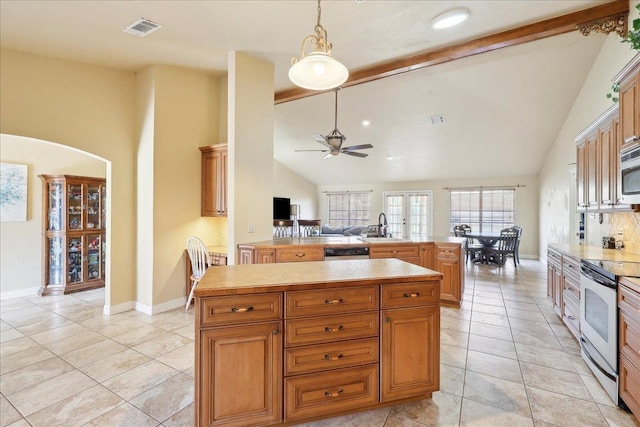 kitchen featuring sink, ceiling fan, hanging light fixtures, stainless steel appliances, and a kitchen island