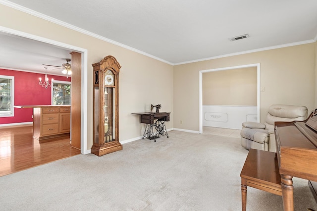 sitting room with ceiling fan with notable chandelier, light colored carpet, and crown molding