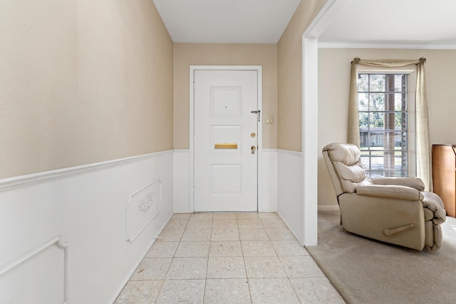 carpeted entrance foyer featuring ornamental molding