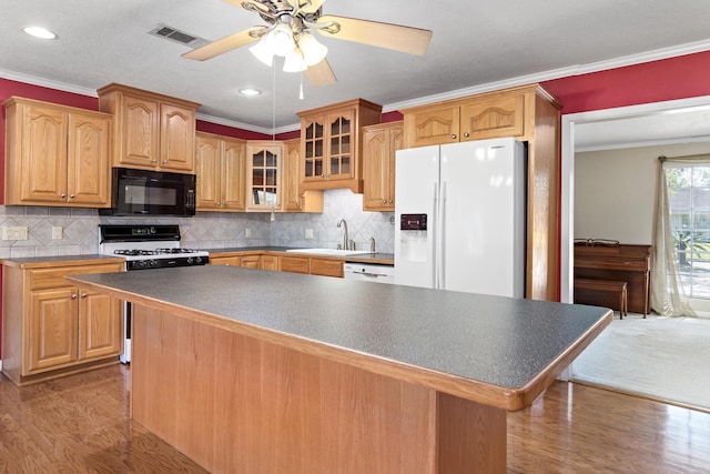 kitchen with white appliances, a center island, ornamental molding, and sink