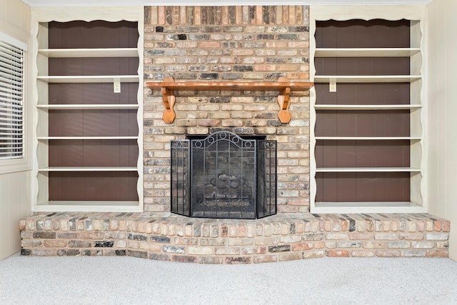 unfurnished living room with carpet, built in features, and a brick fireplace