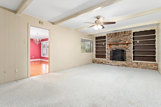 unfurnished living room featuring carpet, ceiling fan with notable chandelier, a brick fireplace, built in shelves, and beamed ceiling