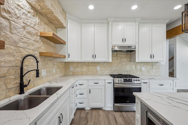 kitchen featuring a sink, under cabinet range hood, stainless steel gas stove, white cabinets, and open shelves