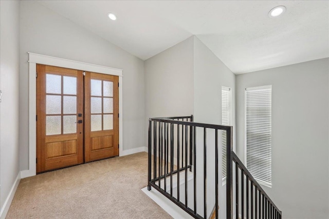 hall featuring vaulted ceiling, french doors, an upstairs landing, and carpet floors